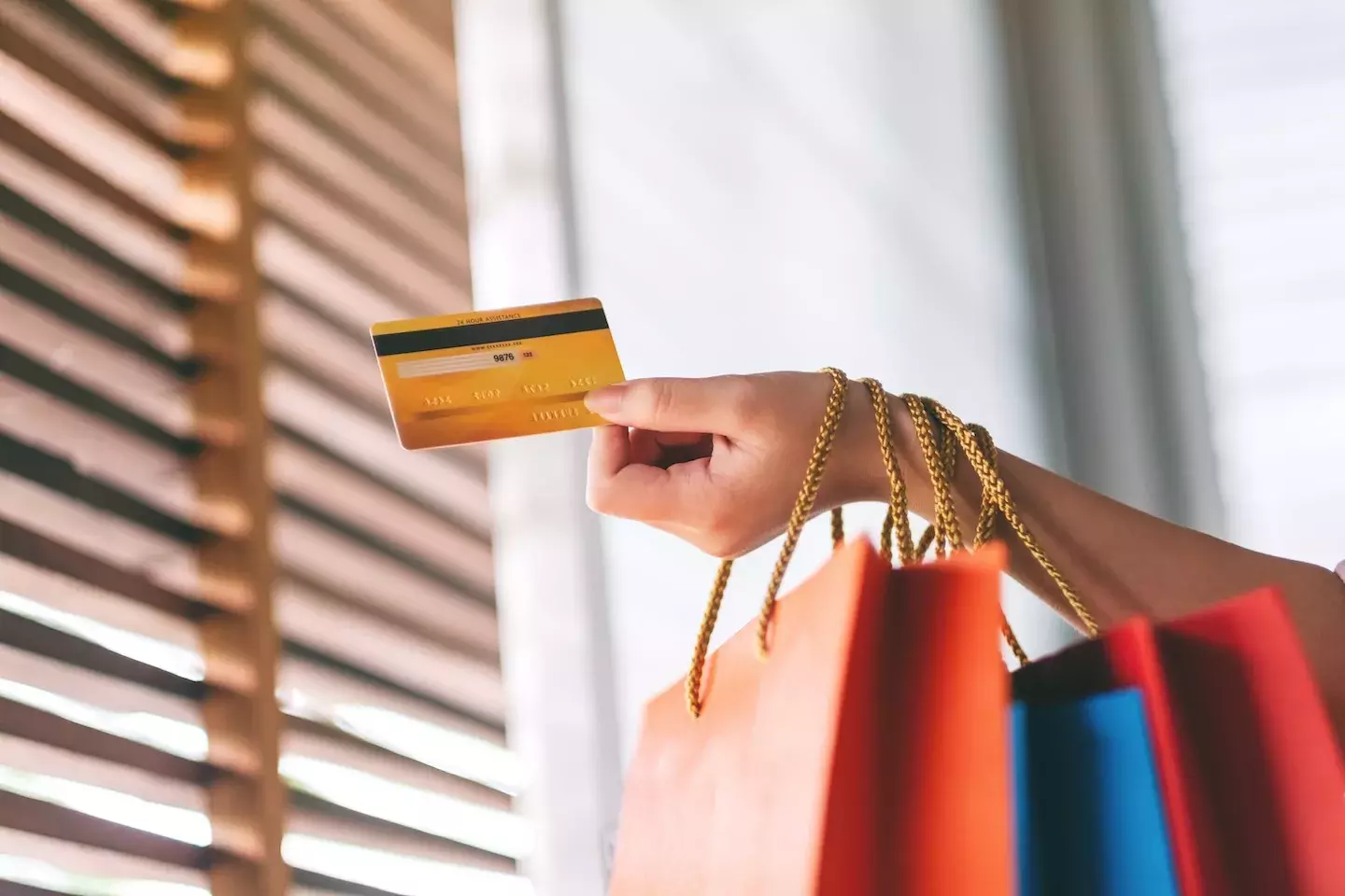 person holding a credit card and shopping bags person holding a credit card and shopping bags